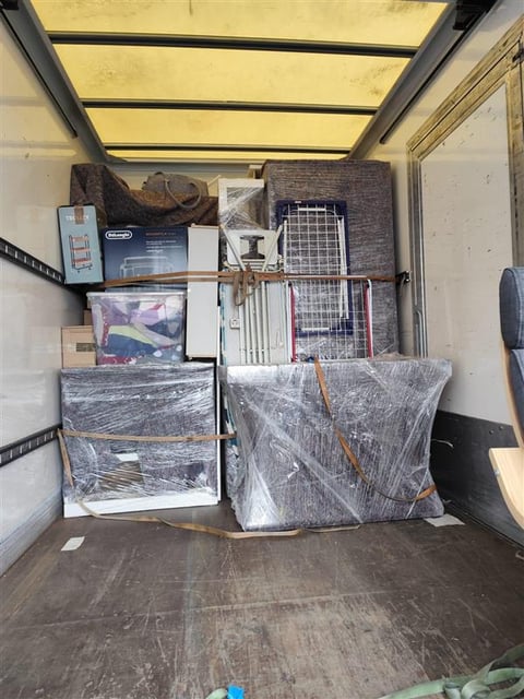 Interior of a moving truck filled with wrapped furniture and household items ready for relocation